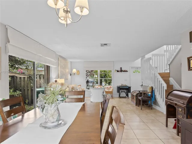 Open floor plan featuring tile flooring, multi-pane windows, sliding glass doors, a decorative chandelier.