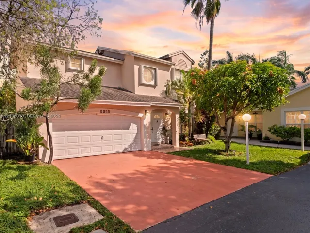 Two-story exterior featuring a stucco facade, an arched entryway, a double-car garage, and a paved driveway