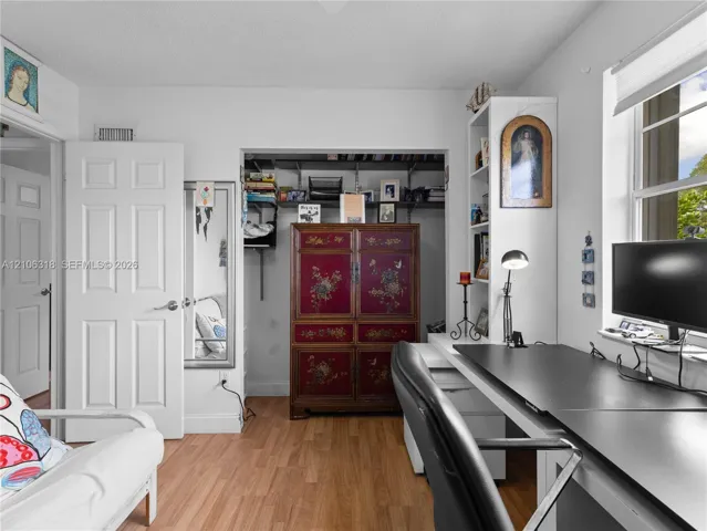 Wood-finish flooring, built-in shelving, expansive closet with open storage, and a multi-pane window