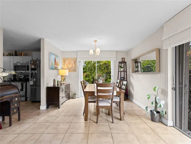 Ceramic tile flooring, neutral wall tones, multi-light chandelier, and large sliding glass doors