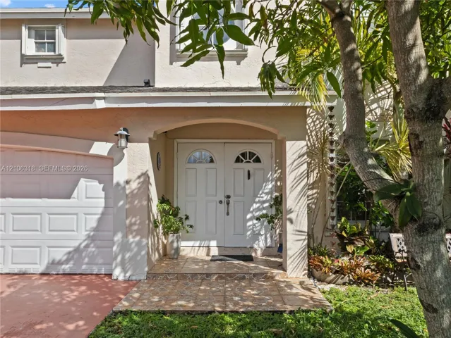 Stucco exterior with a covered entryway, arched portico, double-door entry featuring semi-circular glass inserts, and an attached single-car garage
