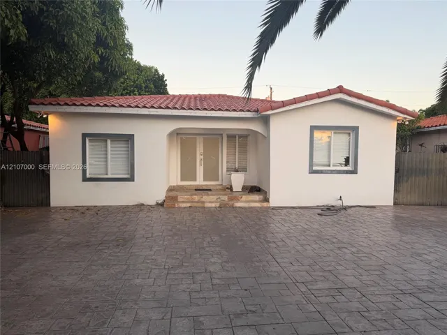 Stucco exterior featuring a terracotta tile roof, stone-finish entryway steps, and double-entry glass paneled doors