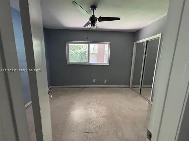 Room featuring a horizontal sliding window, mirrored sliding closet doors, and a ceiling fan with integrated light fixture