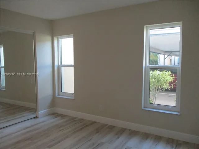 Guest Room featuring wood-finish flooring, dual windows, and a mirrored closet door