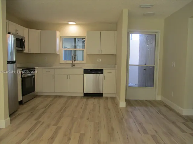 Kitchen featuring white cabinetry, stainless steel appliances, and an exterior door with a screen