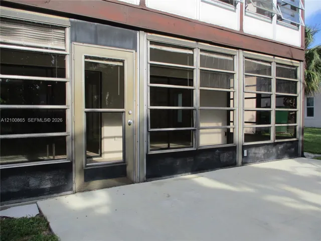 Ground-level patio with a concrete surface, featuring multiple large glass panels, a full-light entry door, and upper-level awning windows