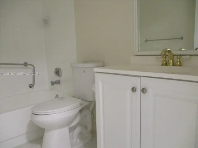 Guest bathroom with White vanity cabinet storage, brass-finish faucet, and integrated sink