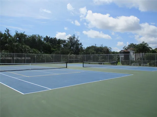 Dual hard-court tennis/pickle ball facility featuring blue and green surfacing, white court markings, central nets, and full-perimeter chain-link fencing