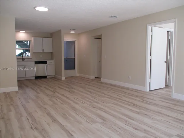 Maple LVP throughout, recessed lighting, white cabinetry, stainless steel dishwasher, and a lightwhite-colored countertop