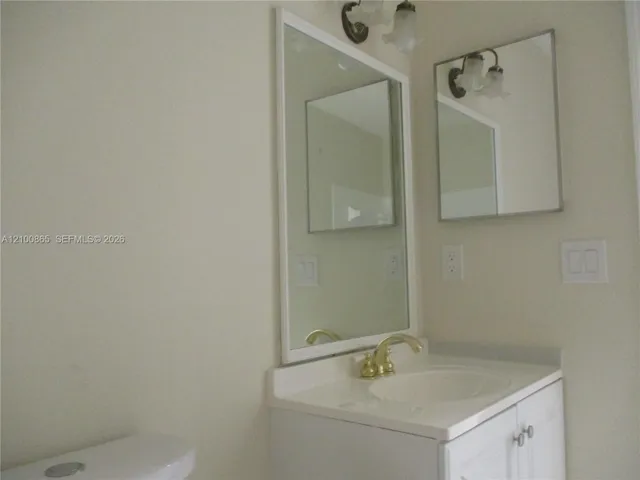 Guest bath with White vanity with a gold-finish faucet, an integrated sink