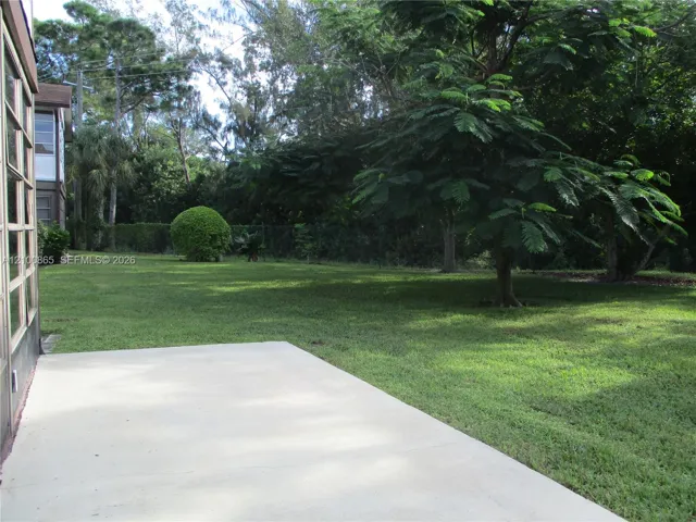 Exterior concrete patio platform, Expansive green lawn with mature trees and a manicured hedge
