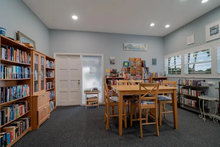 Built-in wood cabinetry, recessed lighting, carpeted flooring, white interior paneled door, and multi-pane windows with integrated shutters