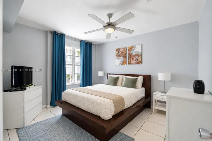 Light-filled room featuring large format tile flooring, a multi-blade ceiling fan with integrated lighting, and a multi-pane window