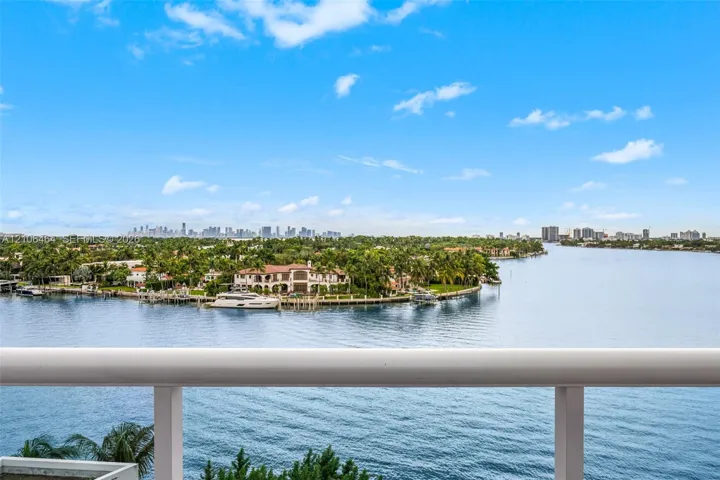 Elevated balcony featuring a tubular metal railing with expansive water, coastline, and skyline scenery