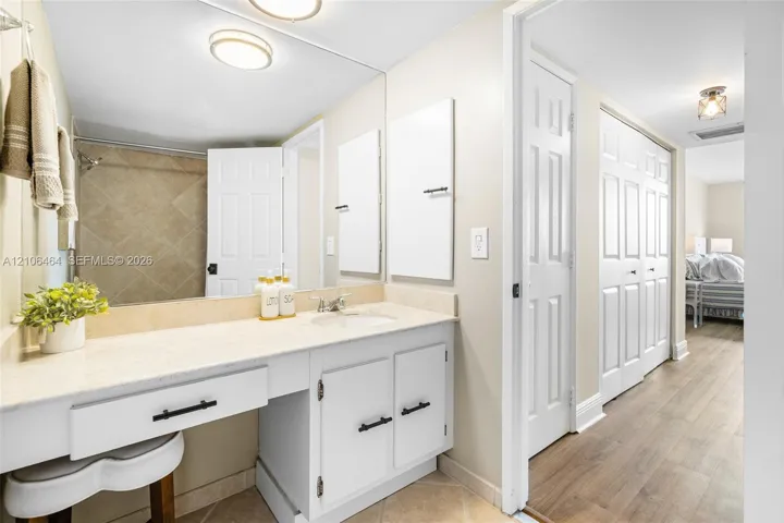 Bathroom featuring a vanity with a light-toned countertop, integrated basin, matte black hardware, and an expansive wall-mounted mirror