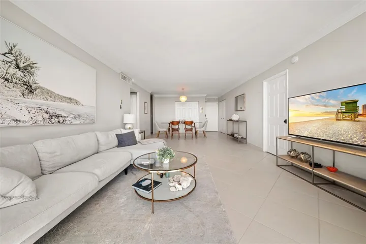 Open-concept interior featuring large-format neutral floor tile, crown molding, and recessed lighting