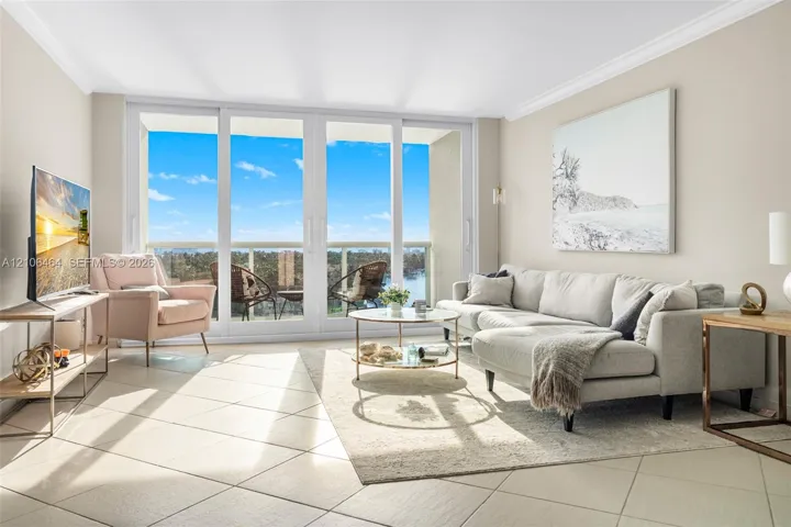 Living area featuring large-format diagonal tile flooring, crown molding, and floor-to-ceiling sliding glass doors opening to a balcony