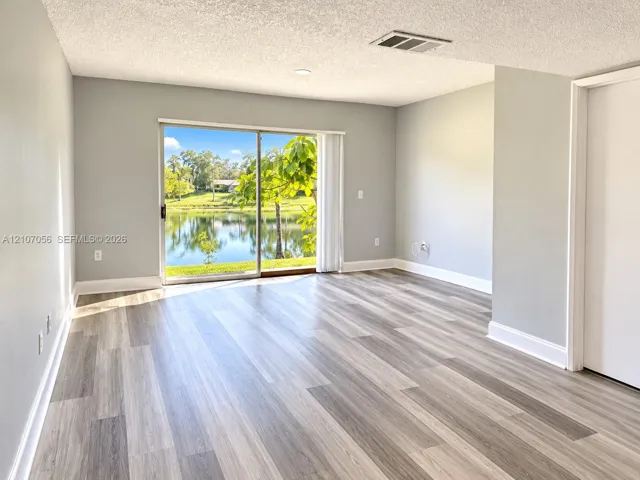 Interior space featuring wood-finish flooring, neutral wall paint, and sliding glass doors opening to a water backdrop