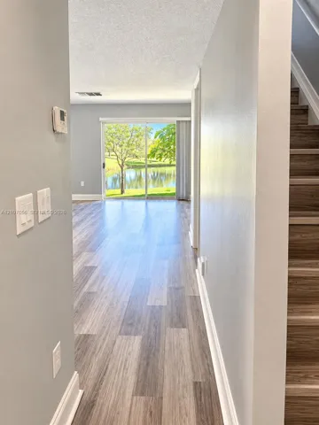 Wood-finish flooring, staircase with wood-finish treads, sliding glass door, and water scenery