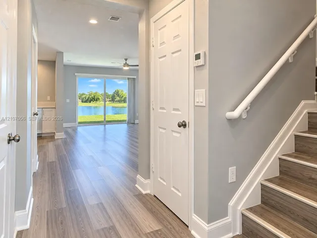 Interior entryway featuring wood-finish flooring, staircase with a white handrail, recessed lighting, and sliding glass doors revealing water scenery