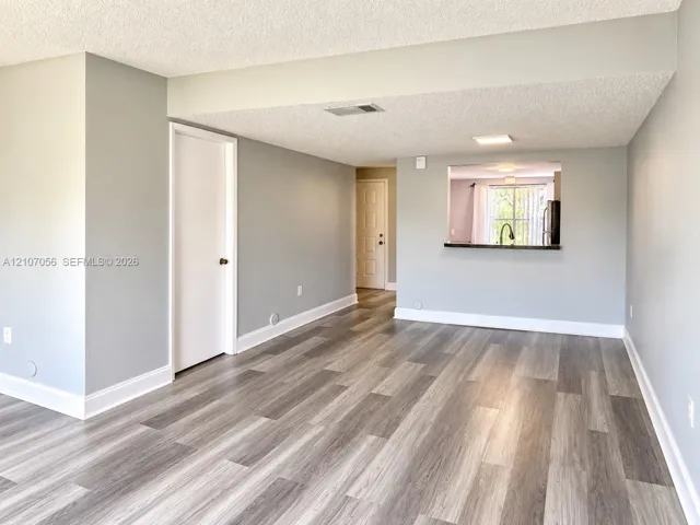 Neutral interior featuring wood-finish flooring, recessed ceiling lighting, and a kitchen passthrough with a counter ledge