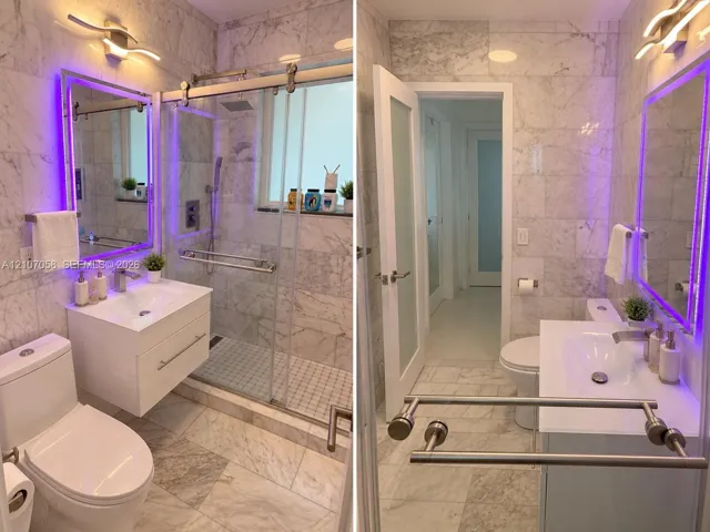 Bathroom featuring floor-to-ceiling stone tile, a modern floating vanity with a white countertop, a walk-in shower with a sliding glass door, and integrated LED vanity lighting