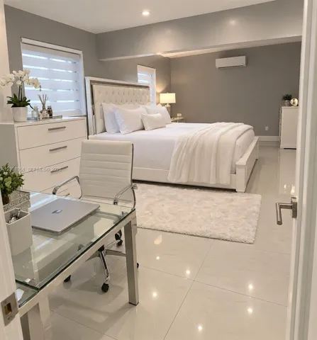 Large-format tile flooring, recessed ceiling lighting, wall-mounted ductless climate control unit, and window treatments with horizontal blinds