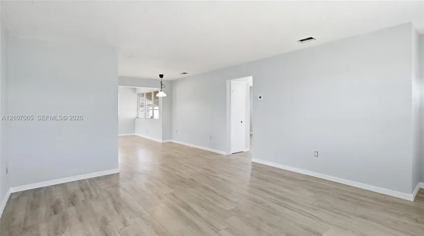 Neutral interior space featuring wood-finish flooring, light-toned wall paint, and a single-pendant ceiling fixture