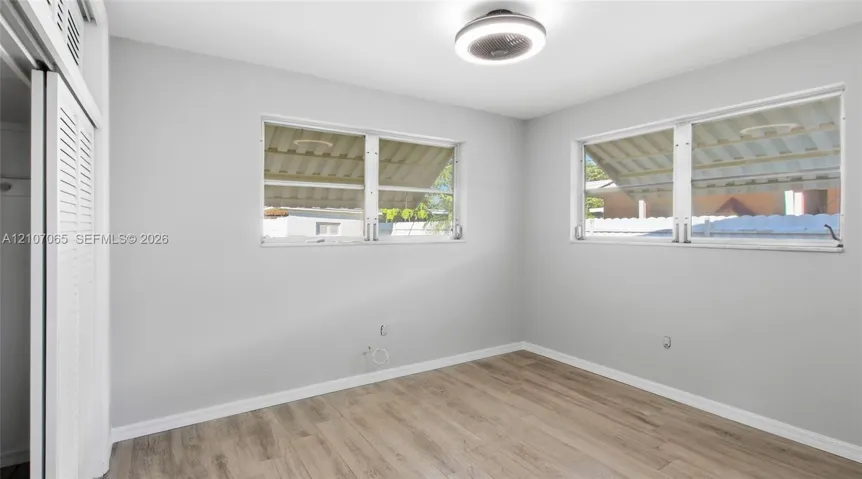 Neutral wall tones, wood-finish flooring, dual windows, and ceiling-mounted light fixture