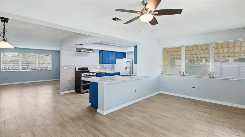 Kitchen featuring a breakfast bar with stone-look countertop, cabinetry with blue finish, stainless steel range, and wood-finish flooring
