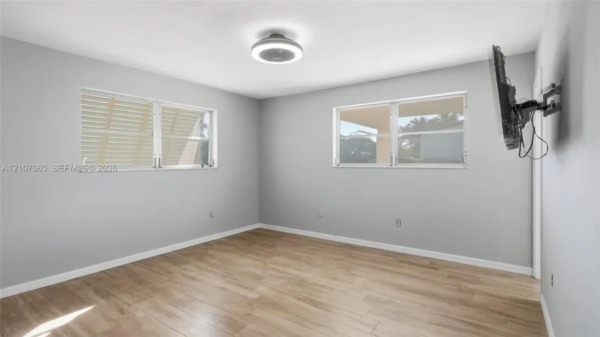 Neutral wall finishes, wood-finish flooring, two dual-pane windows, and a flush-mount circular LED light fixture