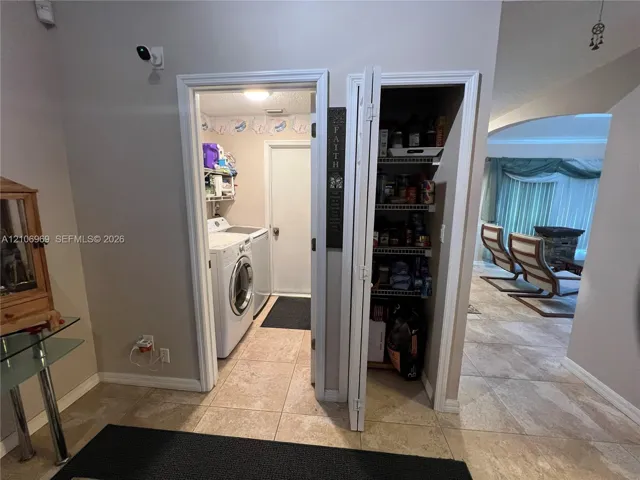 Utility room featuring tile flooring and laundry hookups, paired with a dedicated pantry featuring wire shelving