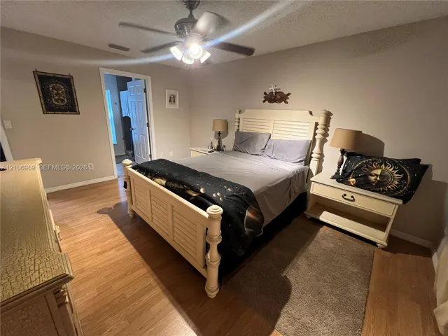 Wood-finish flooring, ceiling fan with integrated lighting, and multi-panel interior door