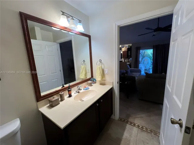 Bathroom featuring a wood-toned vanity with an integrated basin, a light-toned countertop, a full-width mirror with a wood frame, and a three-light wall-mounted fixture