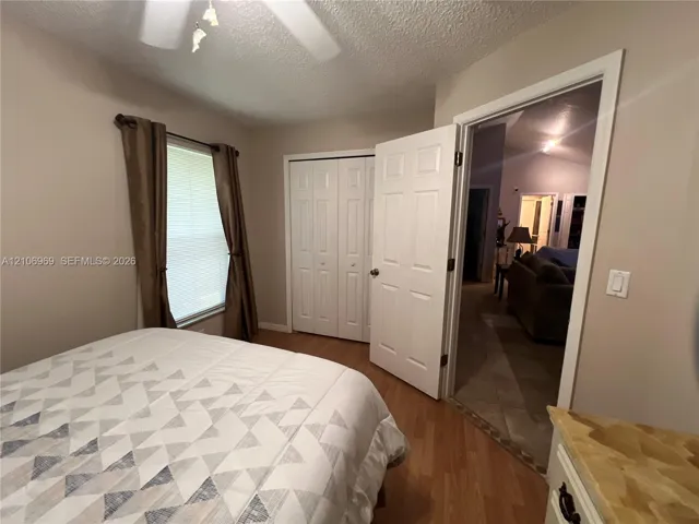 Bedroom featuring wood-finish flooring, a multi-panel interior door, folding closet doors, and a ceiling-mounted light fixture