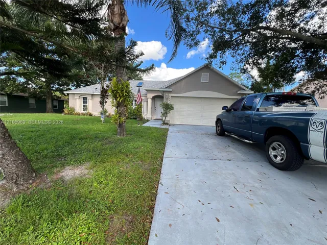 Single-story exterior featuring a concrete driveway, two-car garage, and mature landscaping