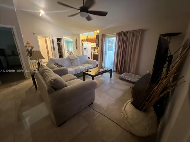 Vaulted ceilings, large-format tile flooring, ceiling fan, and sliding glass door