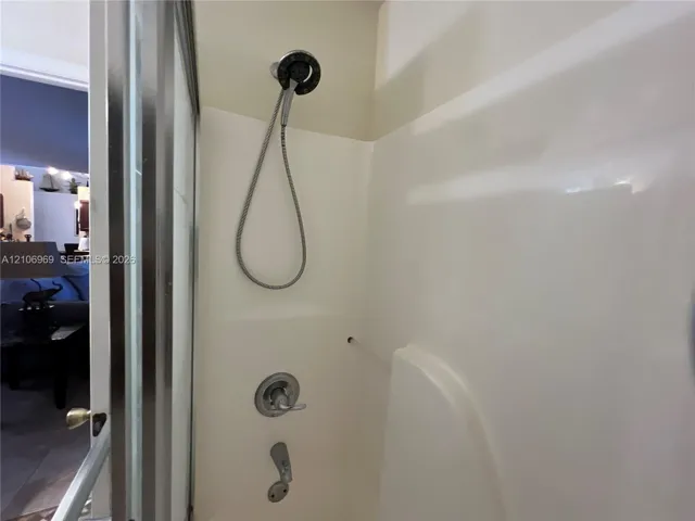 Shower enclosure featuring a multi-setting handheld showerhead, chrome-finished mixing valve, and tub spout with a polished finish