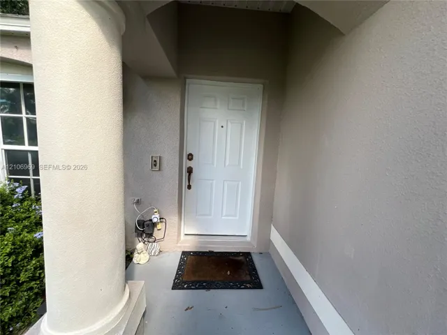 Covered entryway featuring a structural column, six-panel entry door, and multi-pane window