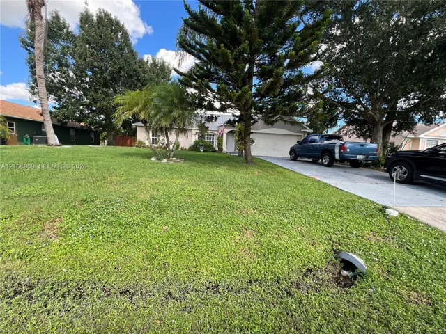 Single-story exterior featuring a concrete driveway, two-car garage, and mature landscaping