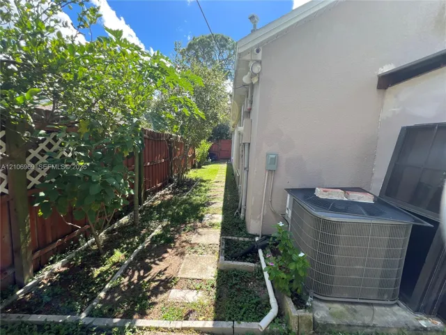 Side yard featuring a concrete paver walkway, wood lattice fencing, and stucco exterior walls
