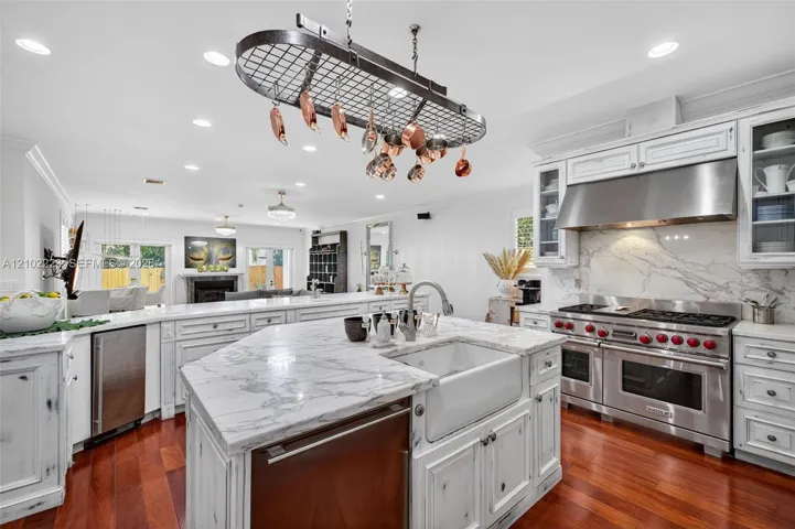 A chef’s kitchen with personality and character featuring distinctive, distressed, finish cabinetry, Premium, Wolf, Appliances, and beautiful marble stone countertops a unique blend of rustic charm and modern culinary luxury creates a space that’s as inviting as it is functional.