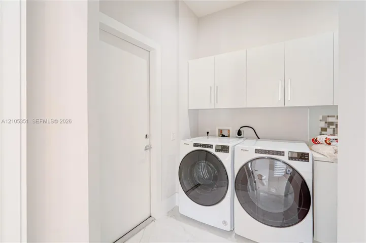 Laundry area featuring white cabinetry, solid-surface flooring, and neutral wall tones
