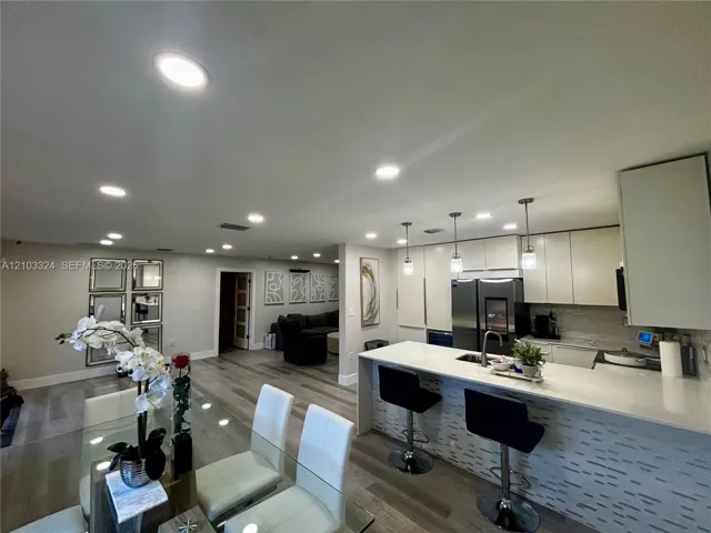 Kitchen featuring flat-panel cabinetry, quartz countertops, a waterfall island, recessed lighting, and pendant fixtures over the breakfast bar