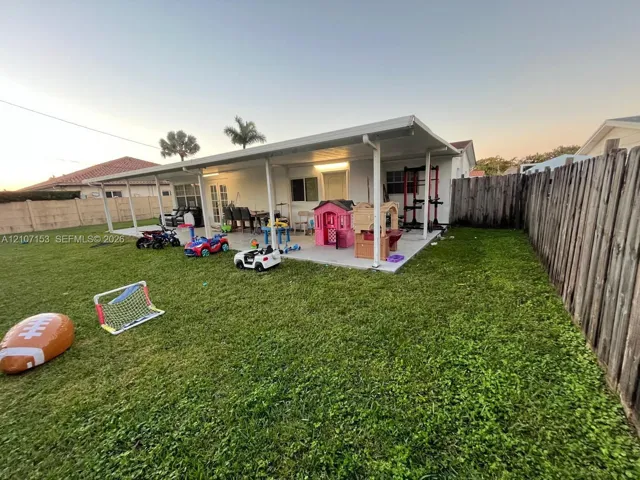 Rear yard featuring a concrete patio, a covered lanai with structural support columns, and full-perimeter wood fencing