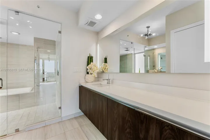 Primary Bathroom with Dual Backlit Sinks, Glass enclosed Shower & Tub as well as Hidden Water Closet.
