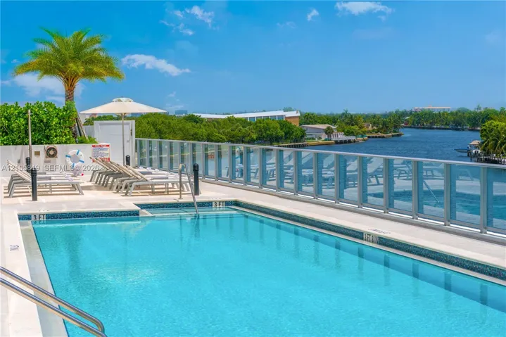 Heated Swimming pool with tile surround, glass panel railing, and paved sun deck