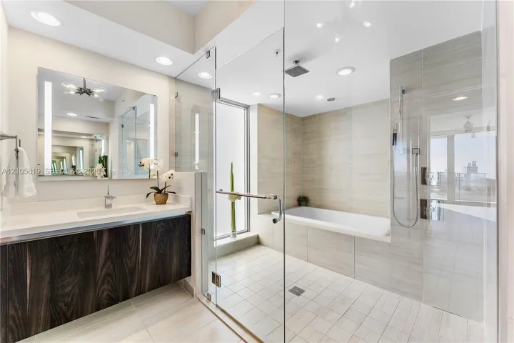 Primary Bathroom with Dual Backlit Sinks, Glass enclosed Shower & Tub as well as Hidden Water Closet.