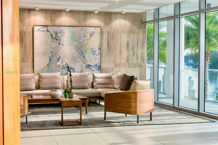 Waterfront Lobby. Floor-to-ceiling glass windows, stone panel wall cladding, recessed ceiling lighting, and large-format tile flooring