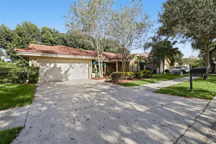Single-story residence featuring a tile roof, light-toned stucco exterior, and a multi-car garage with a concrete driveway